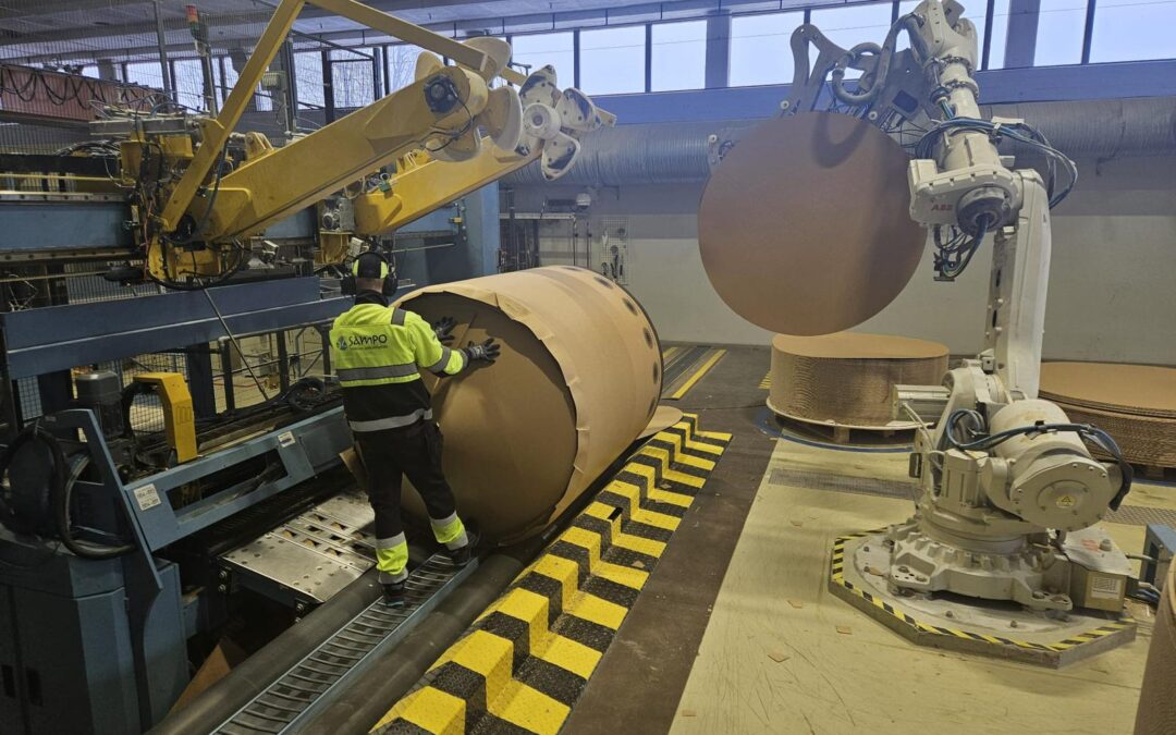 Prosessinhoitaja käsittelee suurta rullaa Stora Enson tehtaalla automaatiolaitteiden ja robottivarren vieressä