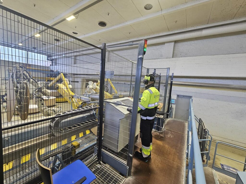 Prosessinhoitaja valvoo automaatiolaitteita Stora Enson tehtaalla turva-aidan takana.